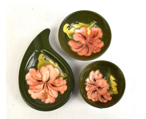 MOORCROFT; three 'Hibiscus' pattern tubeline decorated items comprising two bowls and an ashtray on green grounds, all with i