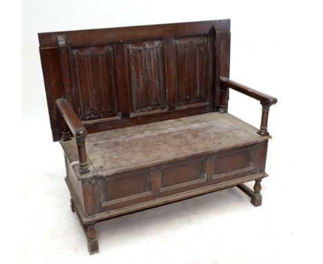 An oak monk's bench with linenfold decoration to the back and raised on baluster turned block supports.
