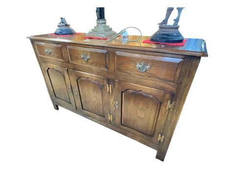 Bevan Funnell Ltd Reprodux oak sideboard having three drawers above three arched fielded panel doors, 84cm x 137cm x 43cm.