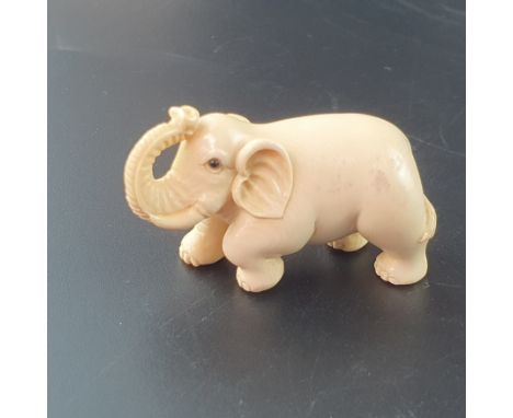 Netsuke - Elefant mit erhobenem Rüssel, Mammutbein, vollrund geschnitzt, dunkel eingelegte Augen, signiert, Himotoshi und Sig