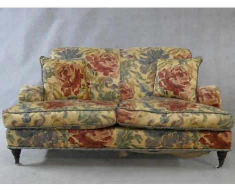 A Howard style sofa in floral upholstery on turned tapering supports terminating in brass and ceramic casters. H.83 W.149 D.9