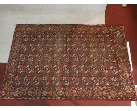 A Bokhara carpet with all over repeating gul motifs on a madder ground contained within stylised floral borders. H.184xW.283c