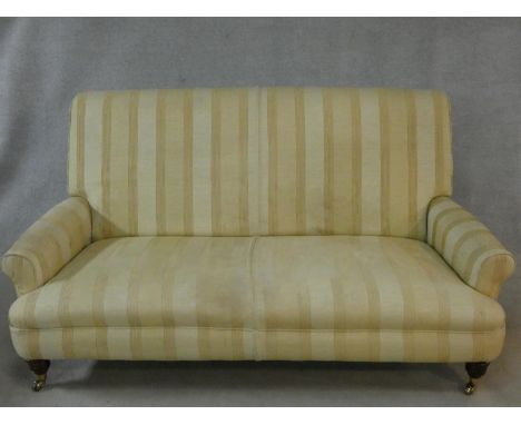 A Victorian style sofa in striped and floral patterned upholstery on turned tapering supports terminating in brass cup caster