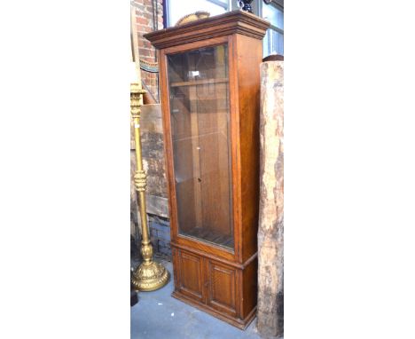 An Army & Navy style late 19th century oak part glazed gun cabinet, fitted for five over a cupboard base enclosing two drawer