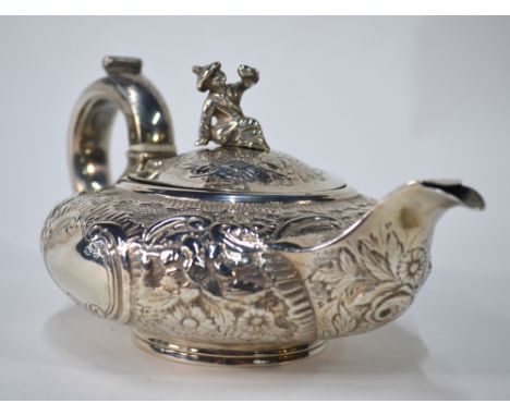 A George IV bachelor teapot of compressed melon form with Chinese Mandarin figural finial and chased and engraved decoration,