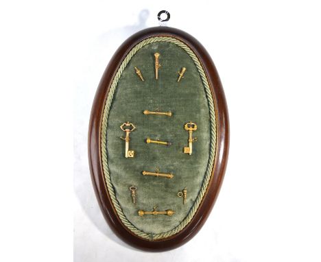 A collection of eleven gilt metal decorative watch-keys - various designs - mounted on a velvet cushion frame