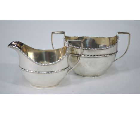 An Edwardian silver oval milk and sugar pair with floral-moulded rims, Haseler Brothers, Birmingham 1907, 7.3 oz