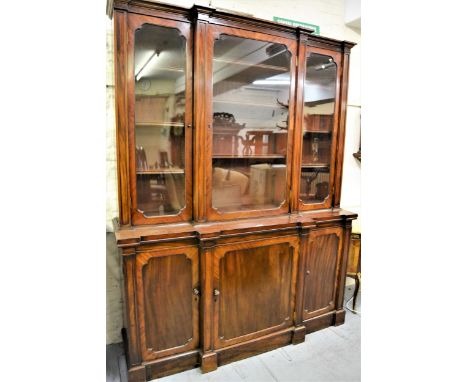 Victorian mahogany breakfront bookcase, the moulded cornice above three glazed doors enclosing shelves, the base with three p