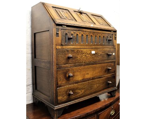 Reproduction oak bureau with three panel fall front above four drawers, together with a similar two door side cabinet with le