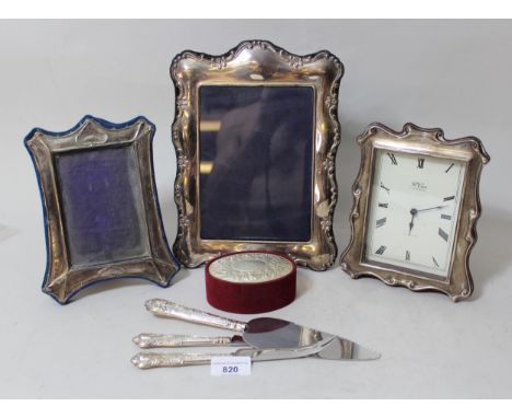 Two modern silver photograph frames, similar table clock, oval silver mounted box, silver handled cake slice and two cheese k