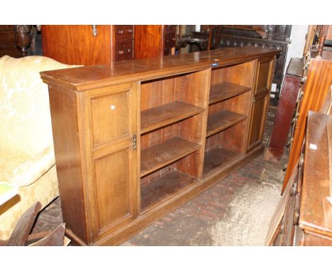 Early 20th Century oak dwarf open bookcase, the moulded top above three open shelves flanked by moulded panel doors on a plin