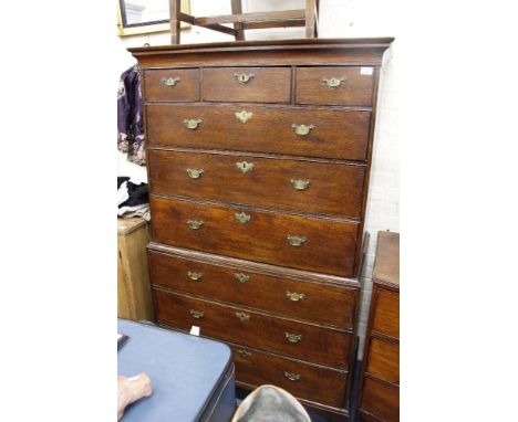 A GEORGIAN OAK TALL BOY with three short drawers and six long drawers, all with brass handles and raised on bracket feet, 100
