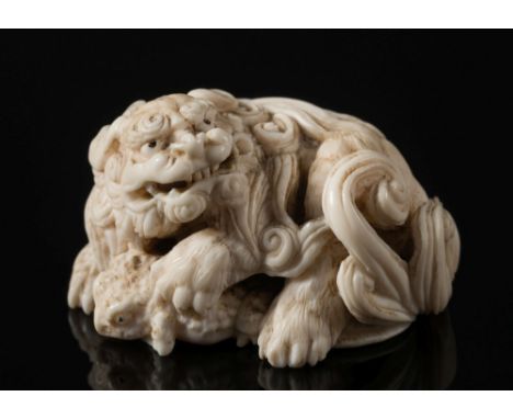 A Japanese carved ivory netsuke of a Shi-Shi and toad: Meiji period, late 19th century, unsigned, 5cm. wide.