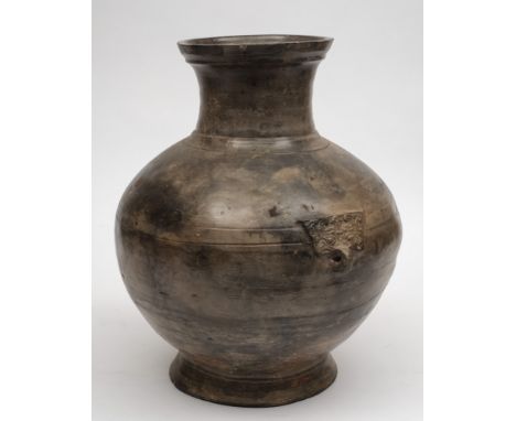 A large Chinese grey pottery jar: of baluster form with incised geometric bands and taotie mask loop handles, probably Han Dy