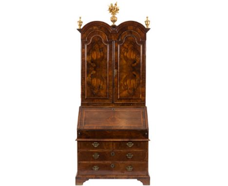 An early 18th Century walnut double dome bureau cabinet:, the upper part surmounted by later giltwood urn finials centred by 