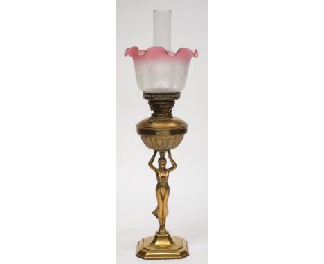 An Art Deco period brass oil lamp: the circular reservoir supported by an Egyptianesque  robed female on a square base with c