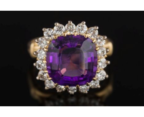 A gold, amethyst and diamond cushion-shaped cluster ring: the cushion-shaped amethyst 10.5mm x 10.0mm in a raised claw settin