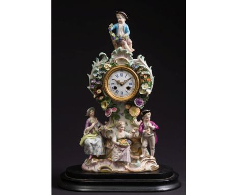 A Meissen porcelain figural mantel clock: of rococo outline, the scroll base with a woman holding a garland of flowers, a chi