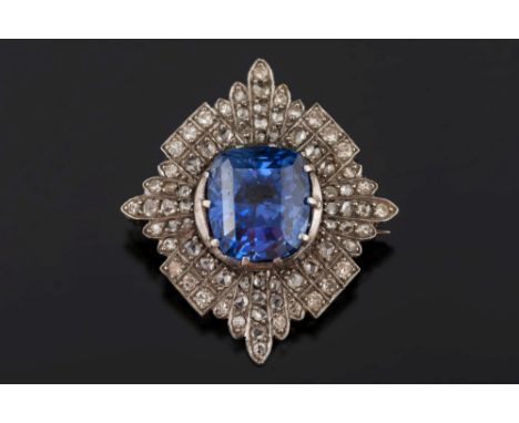 A sapphire and diamond lozenge-shaped brooch: with central cushion-shaped sapphire 10.1mm long x 8.8mm wide x 7.4mm deep, est