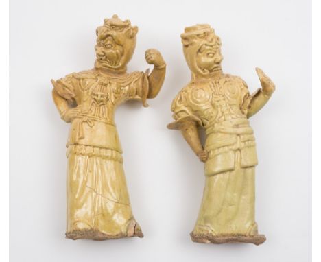 A pair of Chinese straw glazed pottery figures of warriors: each standing with one arm raised in aggressive pose and wearing 