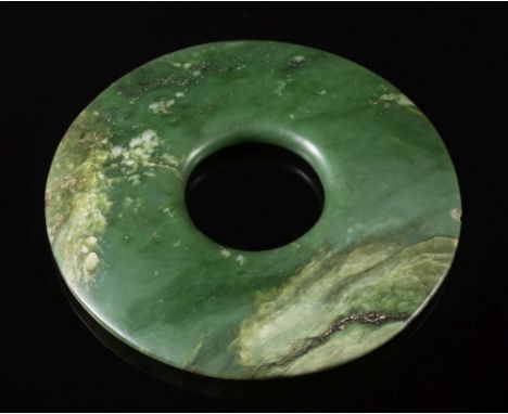 A large Chinese jade disc, Bi : of polished tapering form, the green stone with cream and grey inclusions, bears label 'China