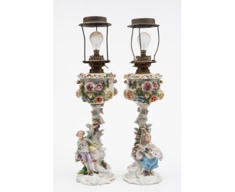 A pair of large Sitzendorf porcelain oil lamps: in the form of a gallant and companion by scrolling columns, the reservoirs a