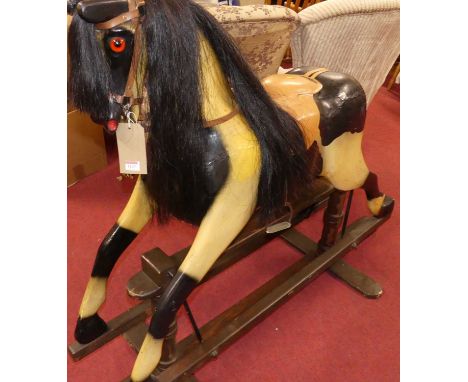 A painted dapple grey rocking horse, with tan metal studded padded leather saddle, raised on a stained pine stand, length 130