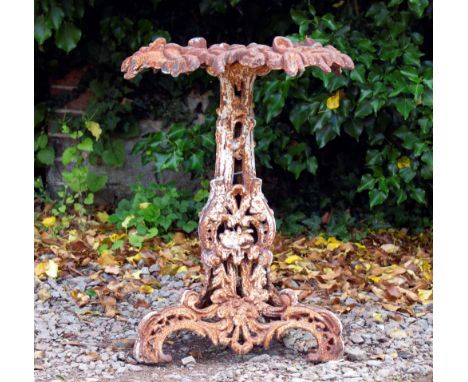 A CAST IRON CONSERVATORY TABLE  of rusticated form with pierced scrolling support and tripod base 49cm diameter x 66cm high 