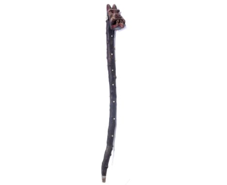 AN UNUSUAL WALKING STICK of naturalistic form, the top carved with a grotesque mask and applied with faux pearls to the shaft