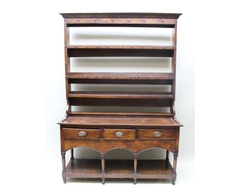AN EARLY 19TH CENTURY OAK DRESSER, the base fitted three drawers with oval brass plate back handles over a triple arch frieze