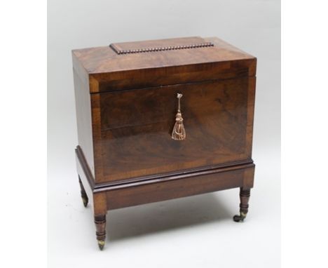 A 19TH CENTURY FIGURED MAHOGANY CELLARET OF BOX FORM with hinged caddy top, opening to reveal a red fabric interior with bott