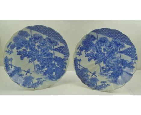 A PAIR OF JAPANESE CERAMIC CHARGERS of slightly fluted form, transfer printed with cobalt blue designs of garden scenes with 