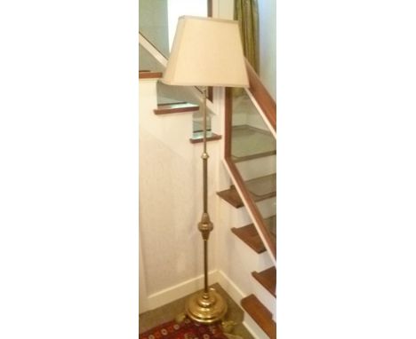 AN EDWARDIAN BRASS FRAMED STANDARD LAMP with telescopic mechanism, raised on circular platform base with three pad feet, fitt
