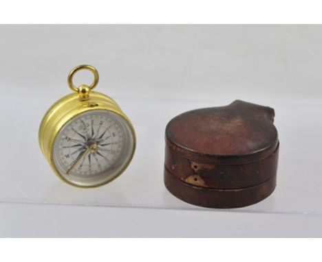 A VICTORIAN GILT BRASS TRAVELLER'S POCKET COMPASS, having ring top, silvered calibrated dial "compensated" and original red l