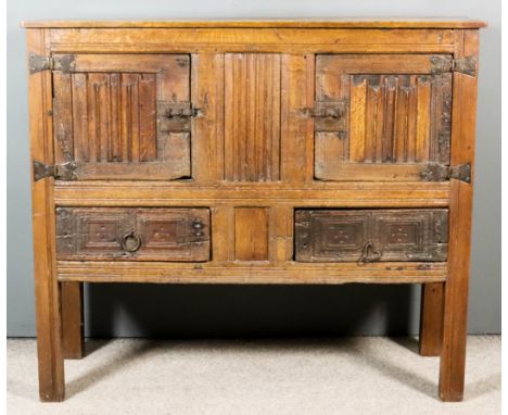 An Old Panelled Oak Aumbry of "16th Century" Design, with plain top and panelled front, fitted with cupboards enclosed by a p