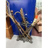 Coalbrookdale style cast iron stick stand with an assortment of wooden walking sticks, a lacrosse