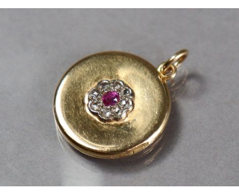 A yellow metal pendant locket of flat circular form, the centre set small ruby within a border of rose diamonds; 21mm dia. (6