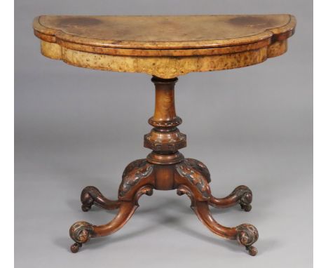 A mid-Victorian inlaid burr walnut fold-over top card table of lobed demi-lune shape, inset green baize, on foliate-carved ce