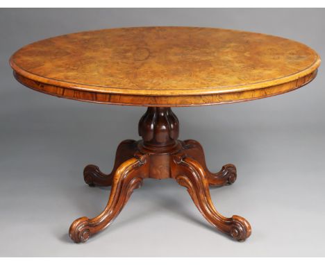 A Victorian burr walnut-veneered oval loo table, the tilt-top with moulded edge, on a turned centre column with four carved s
