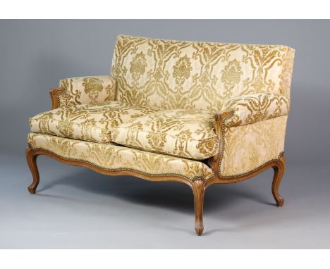 A late 19th/early 20th century carved show wood frame sofa, with shaped arms and cabriole legs, upholstered in old gold moque