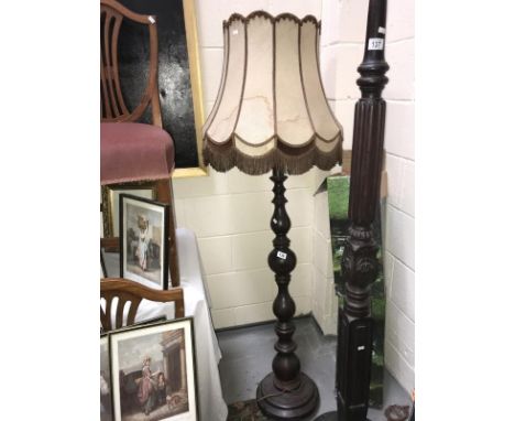 A turned dark wood stained standard lamp with shade.