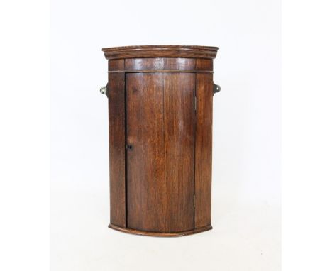 A late 19th century oak hanging bow front corner cupboard, of small proportions, the single door enclosing a single shelf, 60