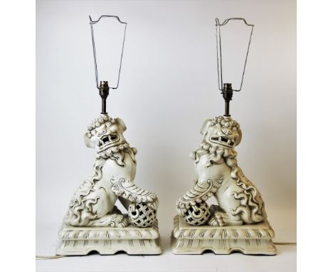A pair of Chinese ceramic lamp bases modelled as Dogs of Fo, with matching shades (one faded), 84cm high overall (2) Lighting