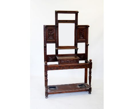 A Victorian carved oak hall stand, the central rectangular bevelled mirror flanked by carved panels and turned spindles, abov