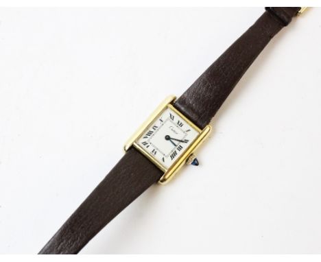 A lady's gold plated Cartier Tank wristwatch, the rectangular cream dial with black Roman numerals, set to a plain polished g