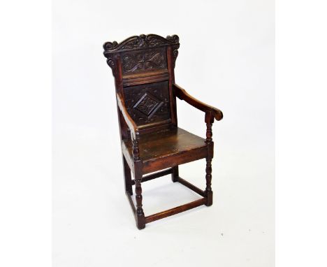 A 17th century and later oak Wainscot chair, the carved pediment with scroll terminals above a panel centred with an incised 