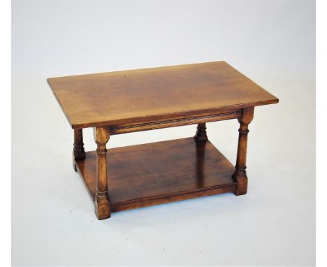 A honey oak coffee table, late 20th century, the rectangular top raised upon turned tapering supports with block feet and a p