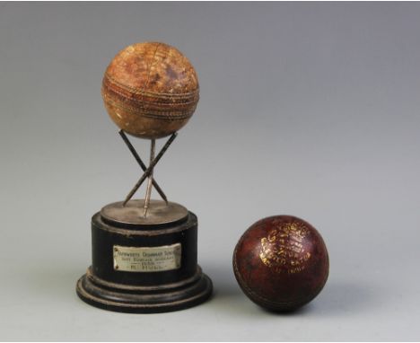 A cricket sporting trophy, comprising three white metal cricket stumps joined as a tripod stand supporting a real cricket bal