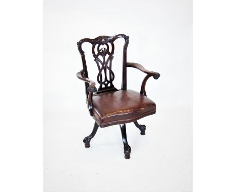 A Chippendale style mahogany revolving desk chair, late 19th century, with a carved and interlaced splat back above out swept