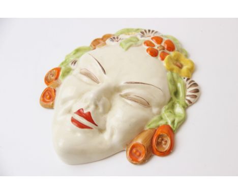 A Clarice Cliff Bizarre wall mask, Flora, circa 1936, relief moulded with floral hair in green, brown, orange and green, 17cm